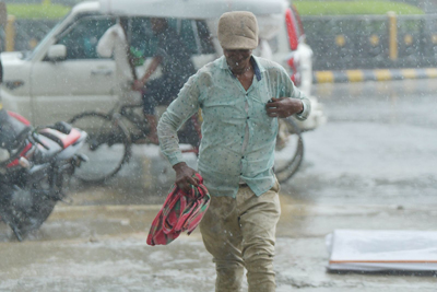 City dwellers move through rain-soaked roads during a heavy downpour in Agartala on May 26.