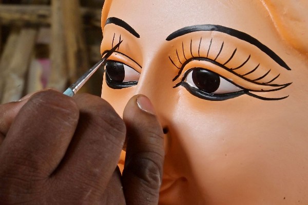 An Idol maker is seen busy in his studio, giving finishing touches to the idol of Mother Goddess Durga .